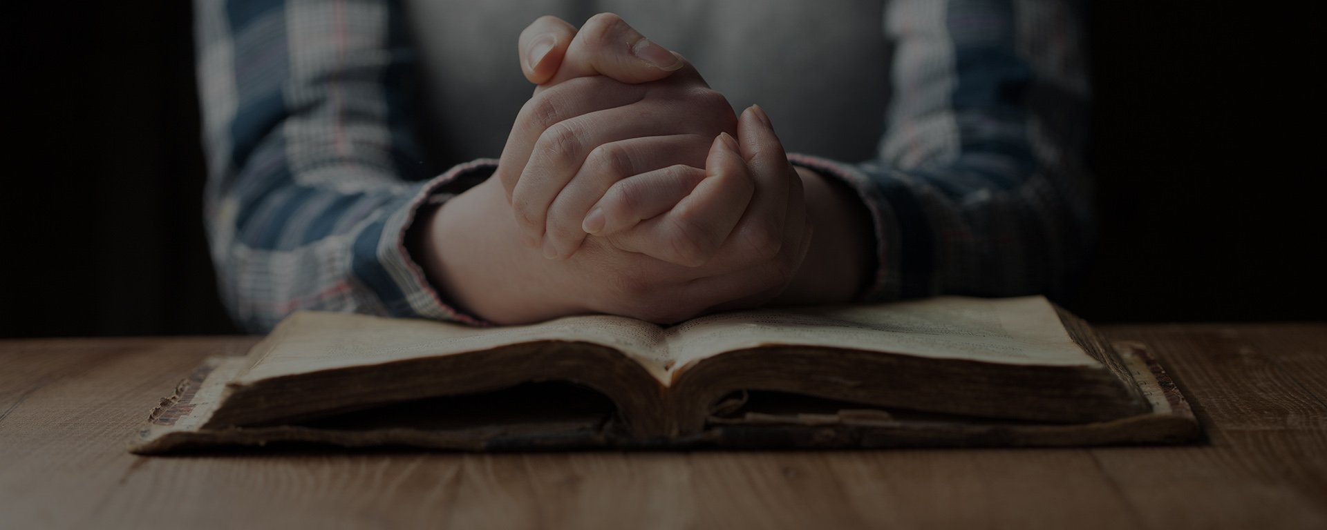 praying hands on Bible | Cornerstone Bible Fellowship, Newton, IA